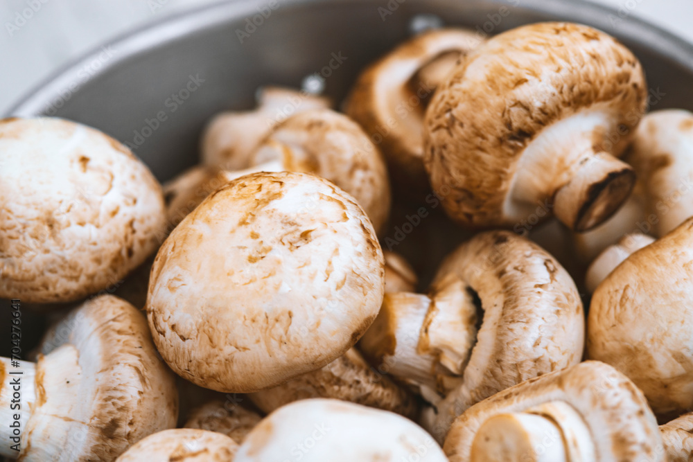 Raw mushrooms in an iron bowl on a white wooden background