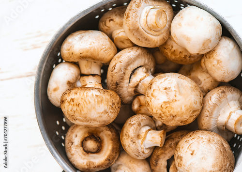 top view of Raw mushrooms in an iron bowl on a white wooden background