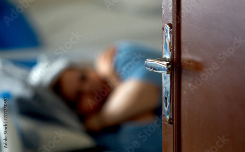 An elderly woman sleeps on a bed behind the open door in a retirement home