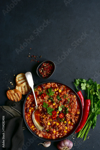 Chili con carne - traditional mexican minced meat and vegetables stew in tomato sauce in a cast iron pan . Top view with copy space.