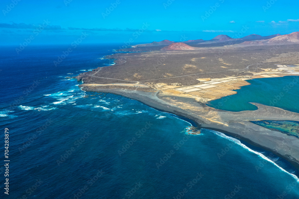 Drone panoramic view of Playa del Janubio in Lanzarote with the volcanic landscape in the background  with turquoise sea and big waves. Nature and tourism.  Canary Islands, Spain.