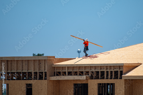 Roofing on roof. Builder roofer install new roof. Construction worker roofing on a large roof apartment building development. Roofer carpenter working on roof structure construction site. © Volodymyr