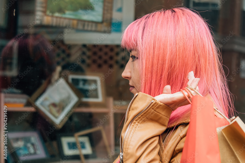 young woman shopping with bags in front of the shop window