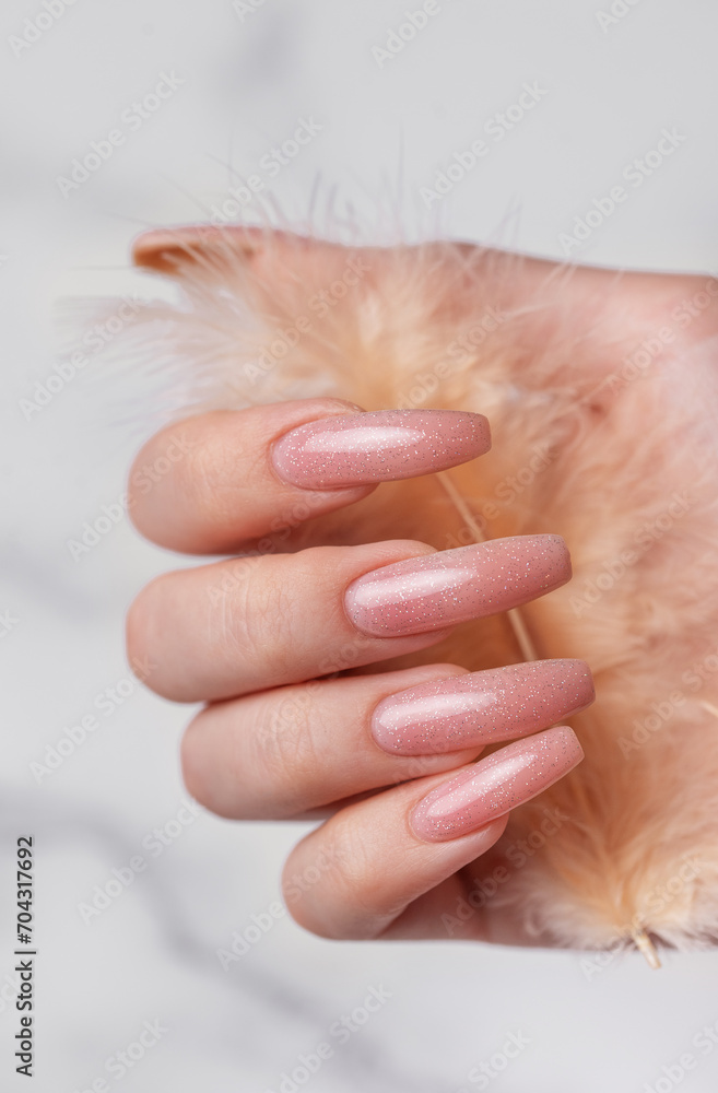 Naklejka premium Female hands with pink nail design hold a feather