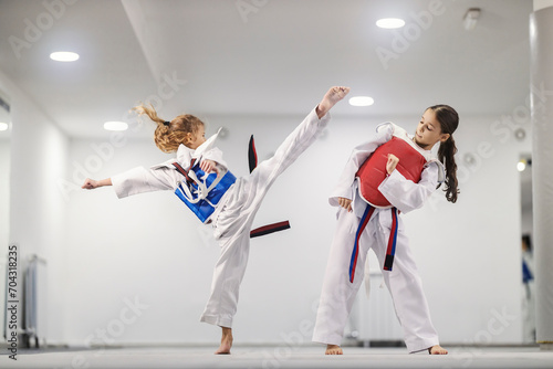Taekwondo girl in dobok is attacking a rival and practicing combat in martial art school. photo