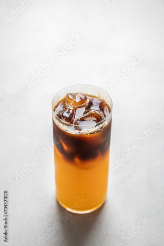 Coffee with orange juice bumble in a glass glass, on a gray background