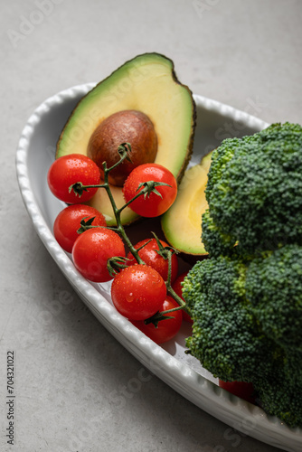 Fresh cherry tomatoes and avacado halves, broccoli close-up. Comfort food concept