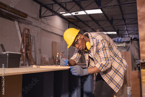 Young affrican american man carpenter, craftman working in wood workshop. Timber industry and furniture industry small business concept. photo