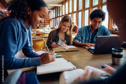 Multiracial group of high school students learning in library.