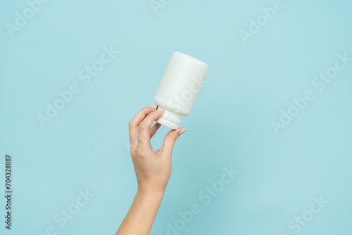 White plastic tube in female hand. Bottle for pill, capsule or supplement. Product branding mockup