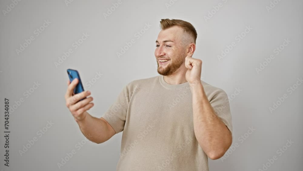 A handsome young man with a beard smiles while video calling on his smartphone against a white background. A handsome young man with a beard smiles while video calling on his smartphone against a white background.