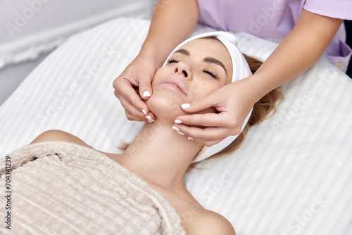 Beautiful woman receiving facial massage in beauty salon. Skin care.
