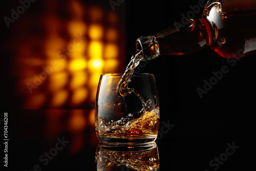 Pouring whiskey from a bottle into a glass.