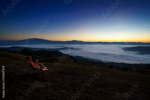 Pretty Asian Woman is happy with the beautiful scenery of the sea of mist in the morning at the Car Camping site with a viewpoint of is fresh nature of the top of Mountain Chiang Mai, Thailand.