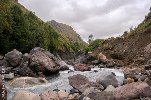 Mountain swift river surrounded by stones and mountain in the background, Caucasus, Russia