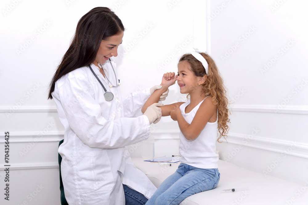 Female doctor smiling and giving medical examination to little girl in clinic