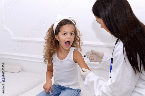 Vaccine fear in children  Little girl in face mask in doctor s office is vaccinated. Crying  scared  afraid of syringe with vaccine  coronavirus  flu  infectious diseases .Clinical trials of injection