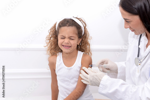 Vaccine fear in children, Little girl in face mask in doctor's office is vaccinated. Crying, scared, afraid of syringe with vaccine coronavirus ,flu, infectious diseases .Clinical trials of injection