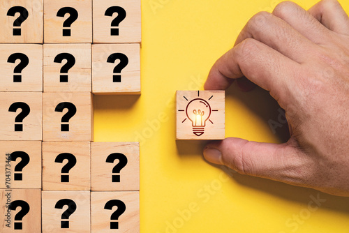 Glowing lightbulb print screen on wooden block cube and move out from question marks for creative thinking idea and problem solving solution concept. photo