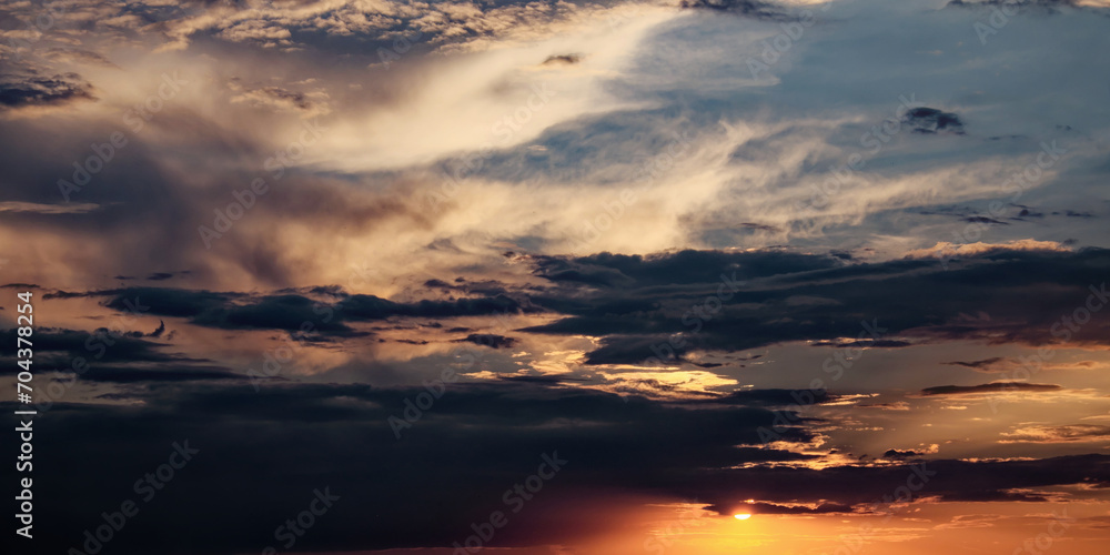 The sky filled with dark clouds and a shining sun at sunset. The sky filled with dark clouds and a shining sun at sunset.