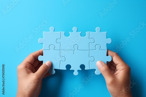Blue puzzle pieces in hand on blue background,