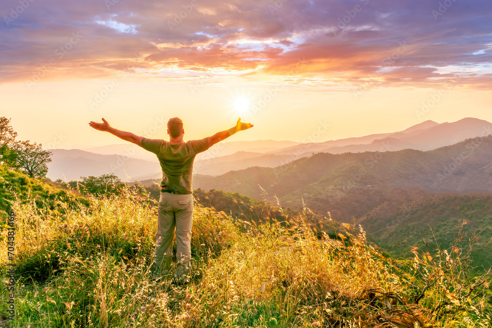 rejoicing man with beautiful scenic mountain sunset landscape on background. happy man watching amazing evening sunset rejoicing man with beautiful scenic mountain sunset landscape on background. happy man watching amazing evening sunset