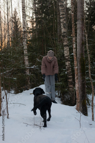 A happy Labrador is playing with his mistress in the snowy forest. walking with pets