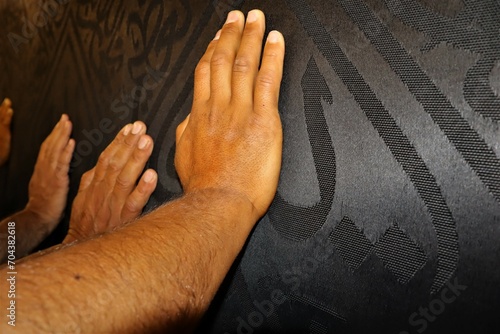 Man's hand touches the Kiswa, worshiping God.
The Kiswa is a great cloth that covers the Kaaba, the sacred stone building at the center of the Great Mosque in Mecca, Saudi Arabia.
Umrah, Hajj. photo
