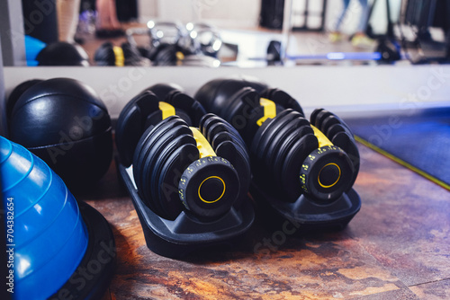 Two modern adjustable dumbbells on stands. Sports equipment in the gym. photo