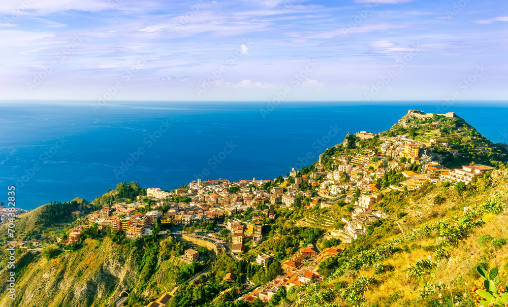 scenic view from highland to a mountain town with beautiful buildings, castles, hills and slopes and panoramic sea gulf with cloudy sky on background