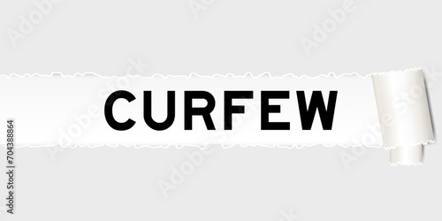 Ripped gray paper background that have word curfew under torn part photo