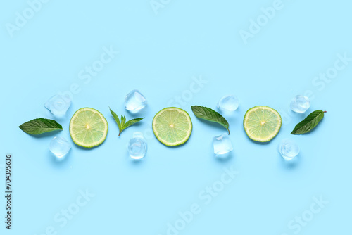 Lime slices with ice cubes and mint on blue background