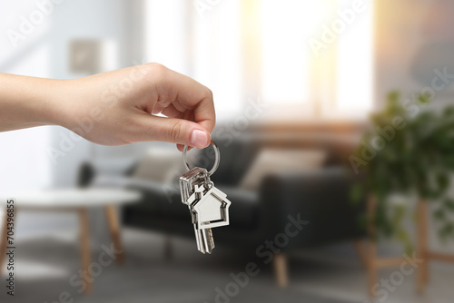 Woman holding house keys in room, closeup