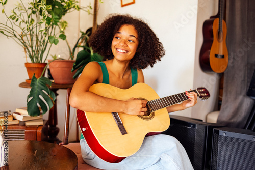 Afro americal young woman playing acoustic guitar. photo