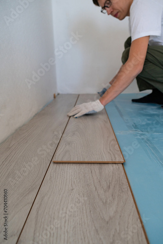 Man is repairing the floor in the house, laminate flooring.