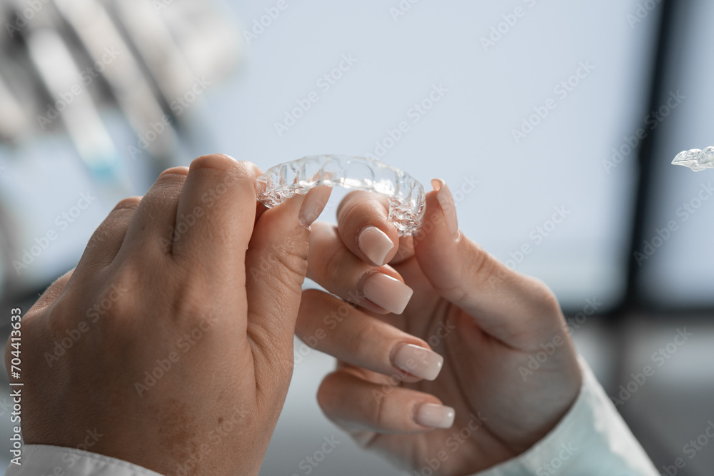 © YURIMA - The dentist carefully holds the mouth guard in his hands, preparing for the procedure and demonstrating his adaptability to the highest standards of dental practice.