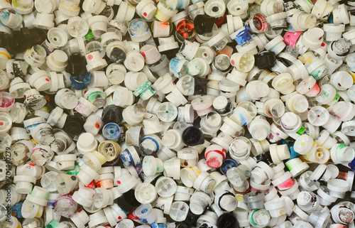 A large number of caps from cans of aerosol paint for graffiti. Smeared with colored paint nozzles lie in a huge pile