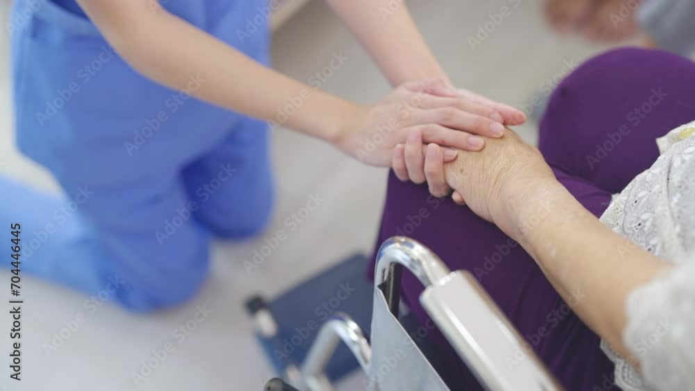 Top view hands of nurse or doctor hold senior woman hands who sit on wheelchair with concept of take care and support elderly people in clinic or hospital center. Top view hands of nurse or doctor hold senior woman hands who sit on wheelchair with concept of take care and support elderly people in clinic or hospital center.