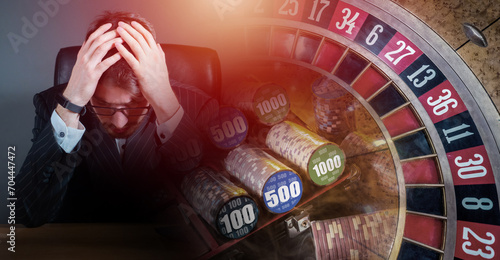 Sad player in casino. Man and roulette table. Guy went bankrupt because casino. Problem gambling addiction. Human gambling addict sits clutching head. Guy went bankrupt due to gambling addiction