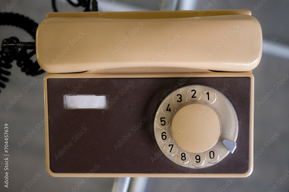Old beige and brown telephone. The five-digit phone number is written on the device panel. Top view. Old beige and brown telephone. The five-digit phone number is written on the device panel. Top view.