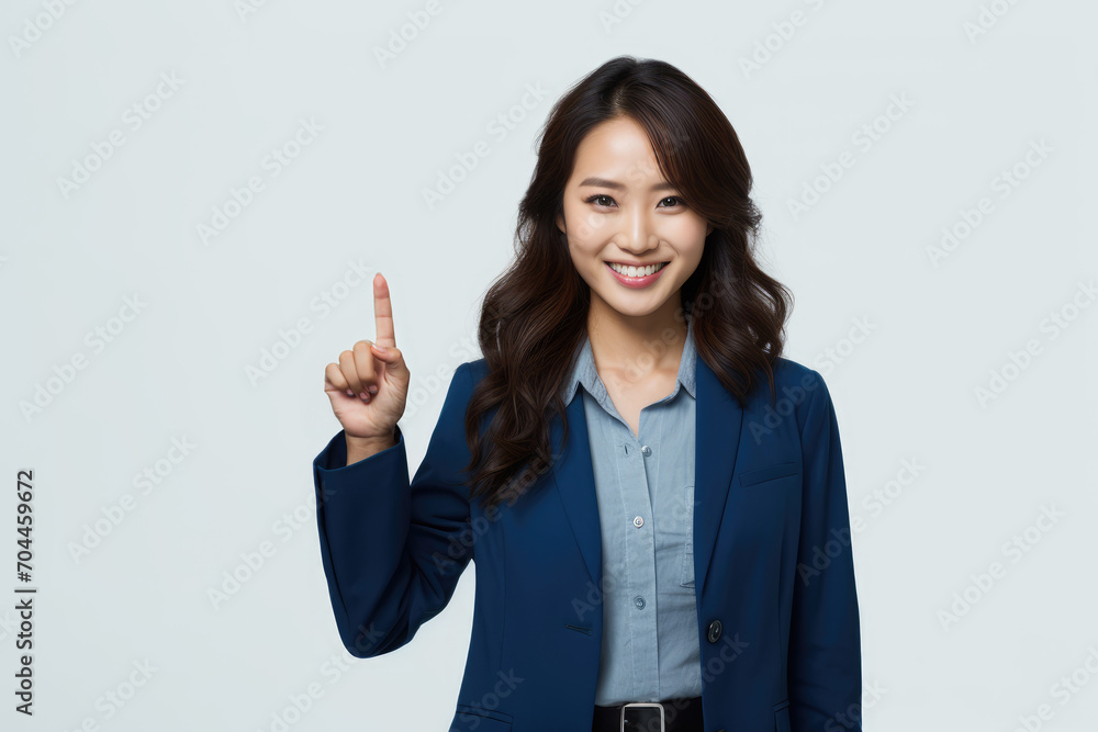 Professional Asian woman in blue business attire pointing upwards to copy space background, smiling on a light background. Professional Asian woman in blue business attire pointing upwards to copy space background, smiling on a light background.