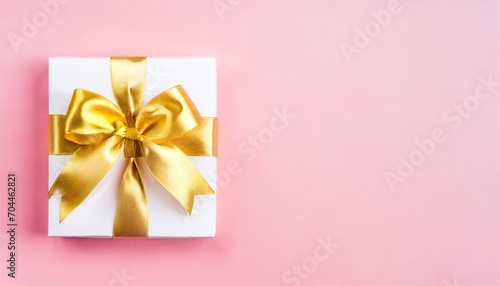 blank gift card with golden bow on pink background top view space for text