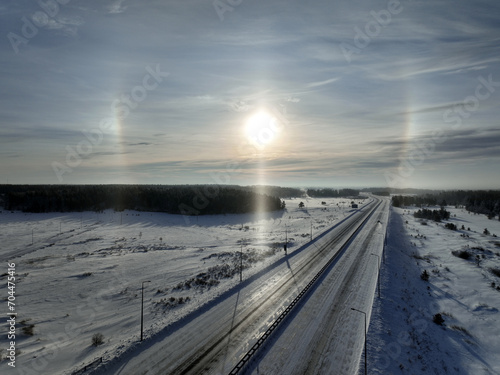 A halo around the sun over the highway in winter time. The ice crystals responsible for the halo are suspended in cirrus clouds in the upper troposphere.