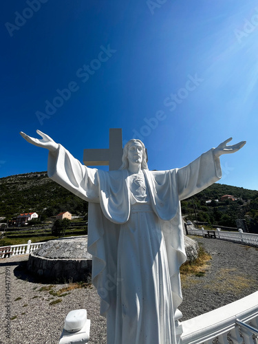 Monument to Jesus Christ and a large cross under the blue sky, above the Cievna canyon. Tourist route on the way to Grlo Sokolova photo