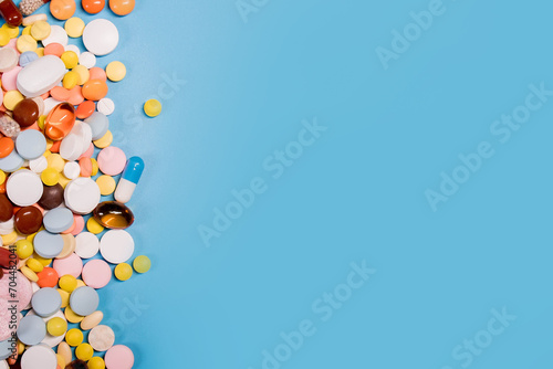 Colorful pills and capsules on blue background. Minimal medical concept. Copy space