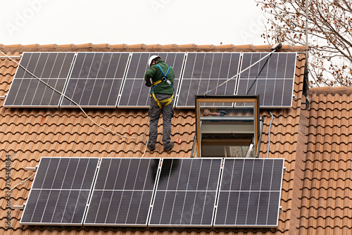 Técnico instalando placas solares en tejado de chalet. photo