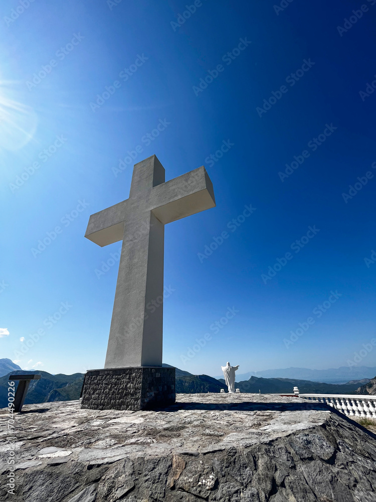 Monument to Jesus Christ and a large cross under the blue sky, above the Cievna canyon. Tourist route on the way to Grlo Sokolova