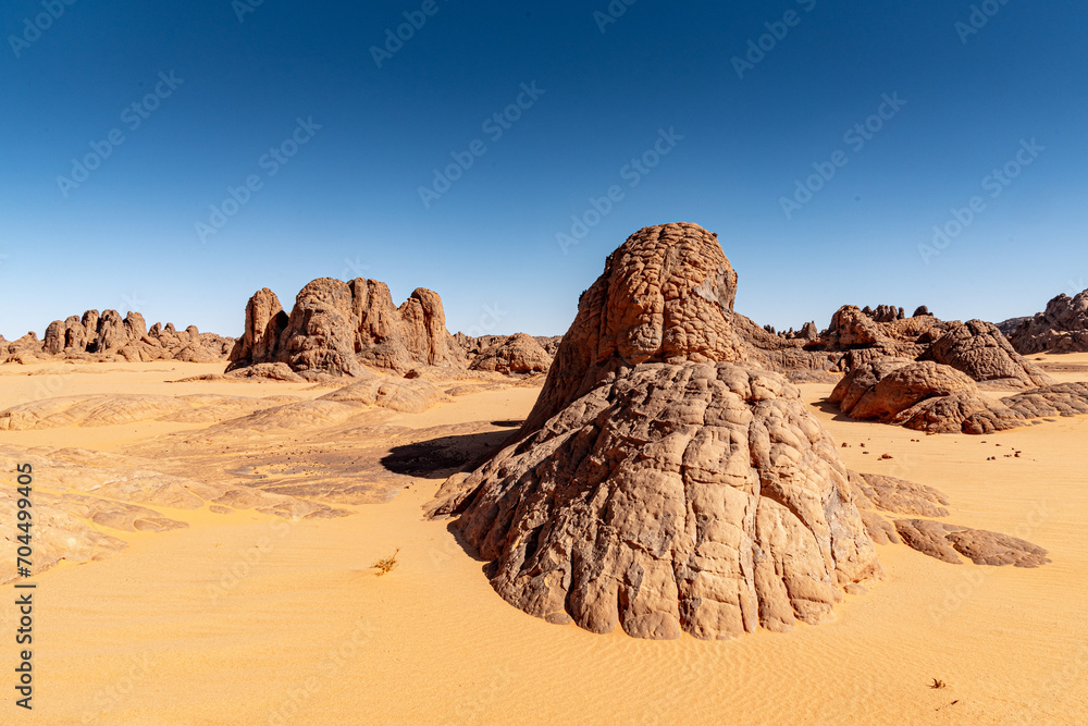 Tadrart landscape in the Sahara desert, Algeria. Sandstone rock formations peeking out from the yellow sand Tadrart landscape in the Sahara desert, Algeria. Sandstone rock formations peeking out from the yellow sand
