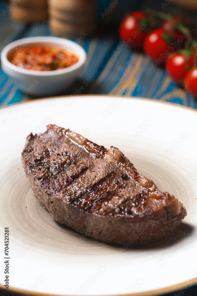 Grilled steak ,cherry tomatoes salt and pepper on wooden table.