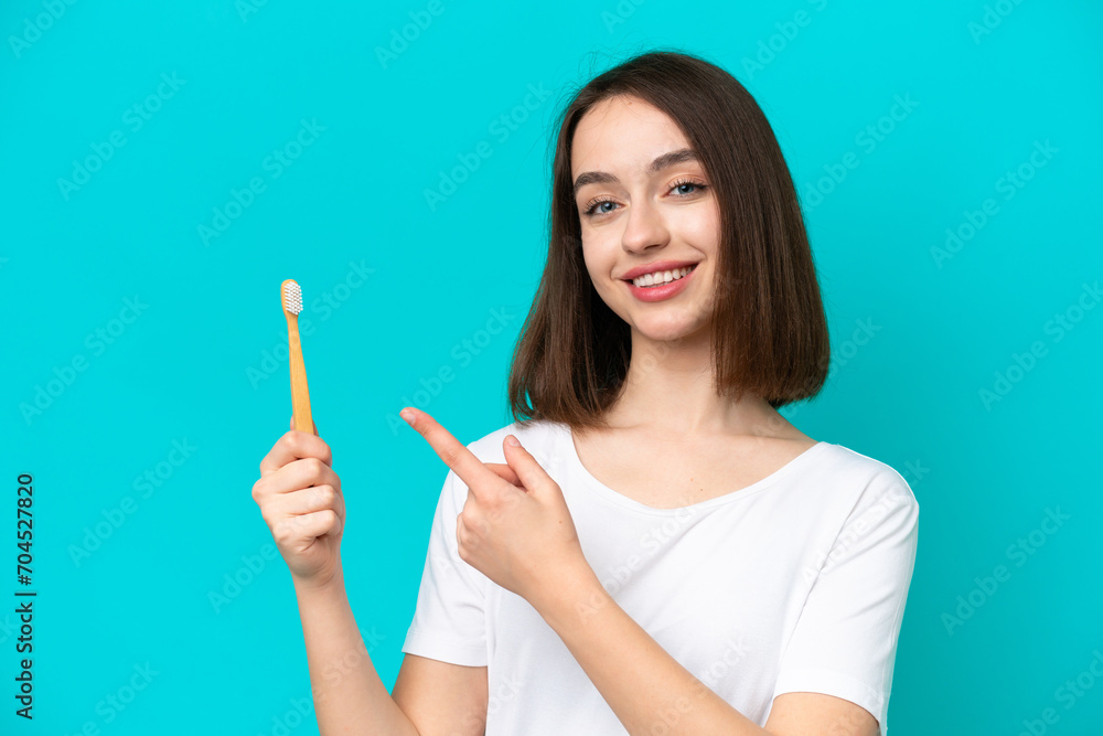 Young Ukrainian woman brushing teeth isolated on blue background and pointing it Young Ukrainian woman brushing teeth isolated on blue background and pointing it